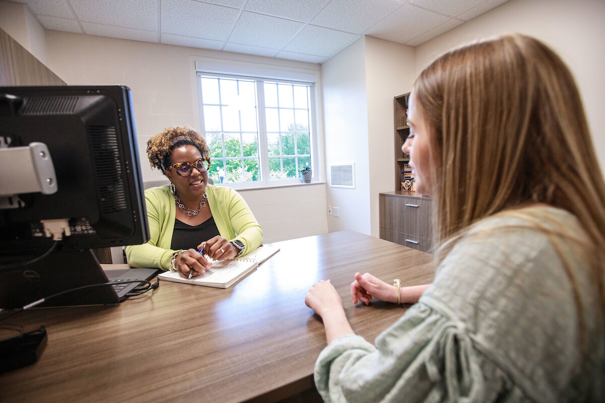 A student and a staff member talk in the staff member's office.